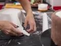 Hände formen weißen Fondant für eine Torte. Hier sind Tipps zum Fondant ausrollen für perfekte Ergebnisse.
