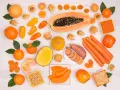 Różnorodne pomarańczowe owoce i warzywa: papaja, marchew, bataty, pomarańcze, morele, kaki, dynia, papryczki.