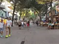 Passeggiata serale nel riccione centro storico, tra negozi e ristoranti all'aperto sotto gli alberi.