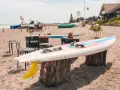 Windsurfbrett am Strand, ein echter Dahme Geheimtipp für Wassersportler. Gelbe Finne ragt aus dem Sand.