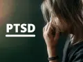 Kobieta z rękami przy twarzy, obok napis PTSD. To pytanie o to, co to jest PTSD i jak wpływa na życie.