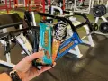 Une main tient plusieurs barres protéinées, parfaites comme collation avant ou après le sport, dans une salle de sport.