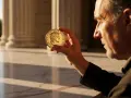 Un homme examine une pièce dorée de 10 centimes Marianne, avec des colonnes en arrière-plan.