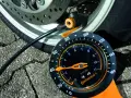 Manometro Continental per pneumatici moto, collegato alla ruota. La lancetta indica la pressione.