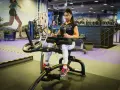 Kvinna tränar på gymmaskin. Hon har på sig träningskläder och fokuserar på sin träning. Hon verkar vara en seriös atlet som tar sin vad press på allvar.