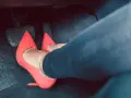 Piedi con tacchi rossi sui pedali dell'auto. Dimostra che si può guidare con i tacchi, con stile e sicurezza.