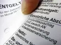 Finger auf Lohnabrechnung, die "Gesetzliche Abzüge" zeigt. Hier wird die Bedeutung der Kirchensteuer lfd. erläutert.