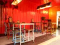 Decoración de restaurante con paredes rojas, mural de vaca y mesas coloridas.