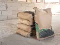 Pile de sacs de ciment sur un chantier. Pour estimer combien de sac de ciment pour 1m3, il faut connaître le dosage.