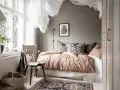 Camera da letto in **stile nordico**, con letto accogliente, tessuti naturali e un tappeto decorativo. L'ambiente evoca un **stile norvegese** rilassante.