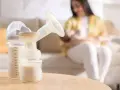 Biberon e tiralatte con latte materno, mentre una mamma allatta il suo bambino. Scopri come aumentare il latte materno in modo naturale.