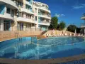 Słoneczna plaża w Bułgarii: basen z leżakami i hotel w tle, idealne miejsce na wakacje.