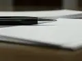 Czarny długopis leży na papierze, gotowy do podpisania ważnego dokumentu, np. pełnomocnictwa.