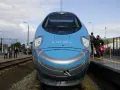 Pendolino Kraków Gdańsk cena: nowoczesny pociąg na torach, pasażerowie czekają na peronie.