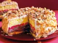 Una fetta di pizza dolce abruzzese, stratificata con crema, cioccolato e confettura, ricoperta di mandorle tostate e scaglie di cioccolato.