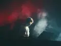 Un DJ dans la fumée rouge et blanche, plongé dans sa musique. Combien de temps avant le traumatisme sonore ?
