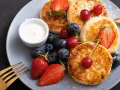 Pyszne placuszki z twarogu, idealne na śniadanie z airfryer, podane z owocami i śmietaną.