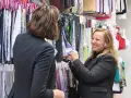Deux femmes discutent devant un mur de tissus. L'une montre un échantillon de vêtement en fibre de bois à l'autre.