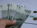 Trzy stuzłotowe banknoty w dłoni, obok dokument ZUS i monety. Czy to zapowiedź 30 krotności ZUS 2025?