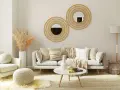 Przytulny salon w stylu scandi chic: jasna sofa, fotel, okrągłe lustra z plecionki, dywan i dekoracje z trawy pampasowej.
