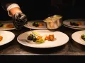 Szef kuchni precyzyjnie serwuje sos, dbając o zasady serwowania dań w stylu "fine dining" na dużych imprezach.