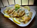 Delicioso pollo al limón con puré de patatas, adornado con perejil fresco y rodajas de limón.
