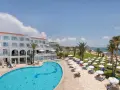 Słoneczny dzień w Akti Beach Village Resort. Basen, leżaki, palmy i morze - idealne miejsce na wakacje.