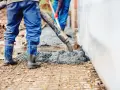 Pracownicy wylewają beton na zbrojenie. Sprawdź aktualną suchy beton cena 1m3.