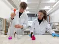 Ragazzi in camice bianco e occhiali protettivi eseguono esperimenti in laboratorio, un passo verso il loro futuro diploma perito chimico.