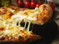 Gorąca pizza z ciągnącym się serem, idealna do pizzy, z pomidorami w tle.