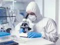 Badacz w kombinezonie ochronnym bada próbki pod mikroskopem. Czy praca w laboratorium jest trudna? Tak, wymaga precyzji i skupienia.