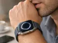 Mężczyzna zamyślony, z dłonią przy ustach, nosi smartwatch z funkcją esim. Elegancki gadżet na nadgarstku.