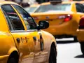 Gelbe Taxis in den USA, ein ikonischer Anblick. Die Spiegelung der US-Flagge im Fenster des vorderen Taxis.