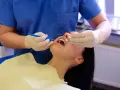 Dentysta wykonuje fluoryzację zębów pacjentki, dbając o ich zdrowie i ochronę przed próchnicą.