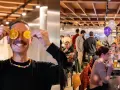 Hombre sonriente con rodajas de naranja en los ojos, en un bar con licencia de bar sin cocina, gente en mesas y globos.