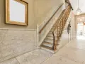 Elegante rellano de escalera comunitaria con mármol y un cuadro dorado. Ideas para decorar rellano escalera comunidad.