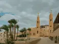 A monastery courtyard with palm trees and a bell tower, evoking the spirit of the desert fathers and mothers.