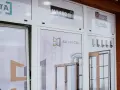 Witryna salonu okien i drzwi z logotypami firm i zdjęciami produktów.