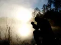 Silhouette eines Mannes, der im Morgennebel kniet und betet. Ein Bild, das christliche Glaubensbekenntnisse widerspiegelt.