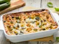 Lasagne di zucchine appena sfornate, dorate e filanti, con zucchine a cubetti e formaggio fuso.