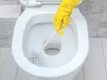 Main jaune pour nettoyer les toilettes.