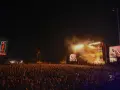 Tłum ludzi na koncercie Żywiec Męskie Granie. Na scenie gra zespół, a na telebimach widać artystów.