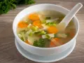 Tazón de sopa de verduras con zanahorias, puerros y perejil.