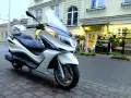 Biały skuter Piaggio X10 125, z kaskiem na siedzeniu, zaparkowany przed kwiaciarnią. Dane techniczne tego modelu są imponujące.