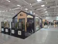 Stoisko targowe z oknami i drzwiami, z ekspozycją okien i ludźmi oglądającymi ofertę.