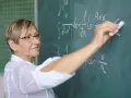 Nauczycielka matematyki pisze na tablicy wzory. Czy to zapowiedź podwyżki dla nauczycieli? Najnowsze wiadomości.