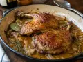 Deux cuisses de canard dorées mijotent dans une sauce savoureuse avec des oignons et des herbes. Un plat réconfortant prêt à être dégusté.