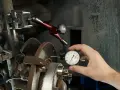 Mechanik mierzy bicie przy hamowaniu tarczy hamulcowej za pomocą czujnika zegarowego.