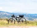 Rower gotowy do bike packingu, z sakwami na kierownicy i pod siodełkiem, na tle górskiego krajobrazu.