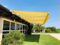 Tende da sole sconto in fattura, gialle e moderne, proteggono un edificio con ampie vetrate da un sole splendente.